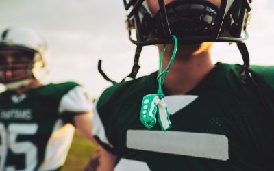 Closeup of a young American football player with his mouthguard hanging from his helmet during an afternoon practice